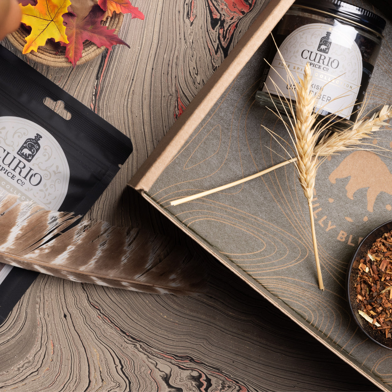 Curio Spice Co. products on a wooden surface with fall leaves and a feather.