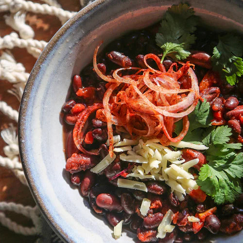 Photo of a bowl of vegetarian chili with toppings.