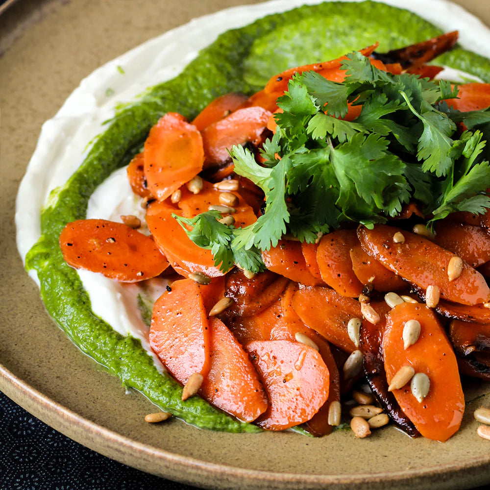 Photo of caramelized carrots on top of a yogurt sauce