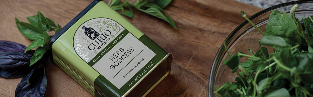 Curio Herb Goddess product on a wooden surface with fresh herbs.