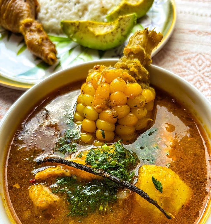  bowl of soup with corn on the cob and garnishes, served with rice and avocado