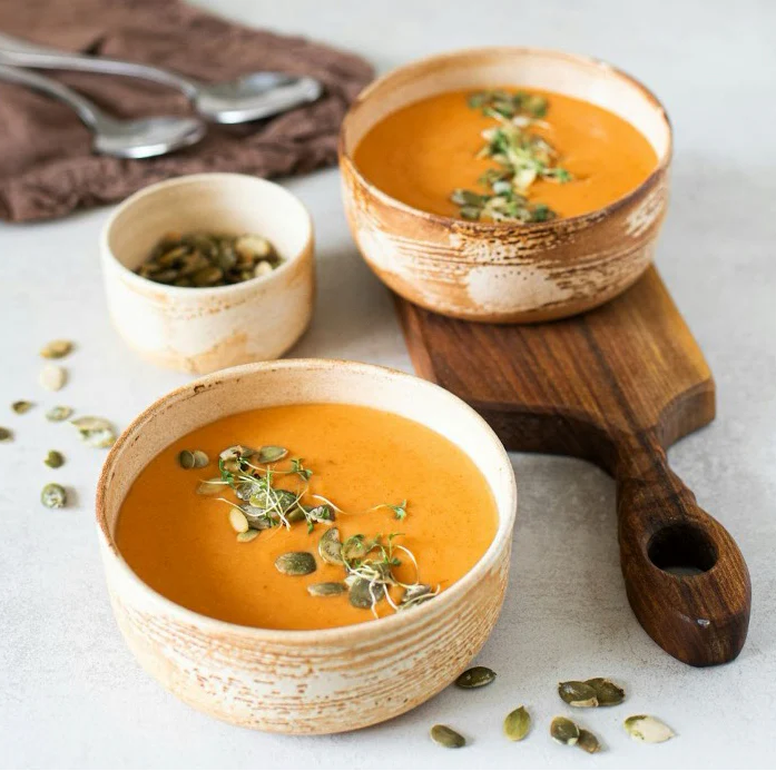 Two bowls of creamy curried pumpkin soup.

