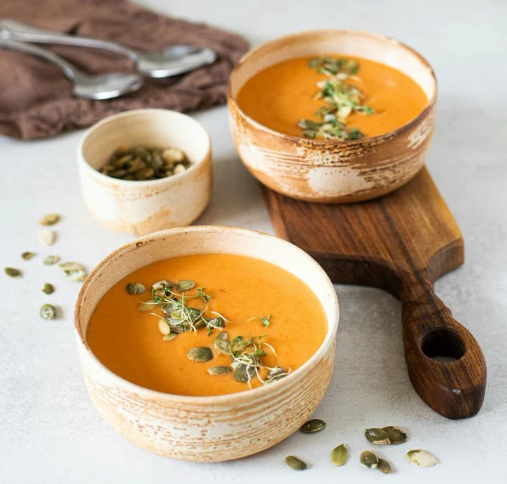 Two bowls of creamy curried pumpkin soup.

