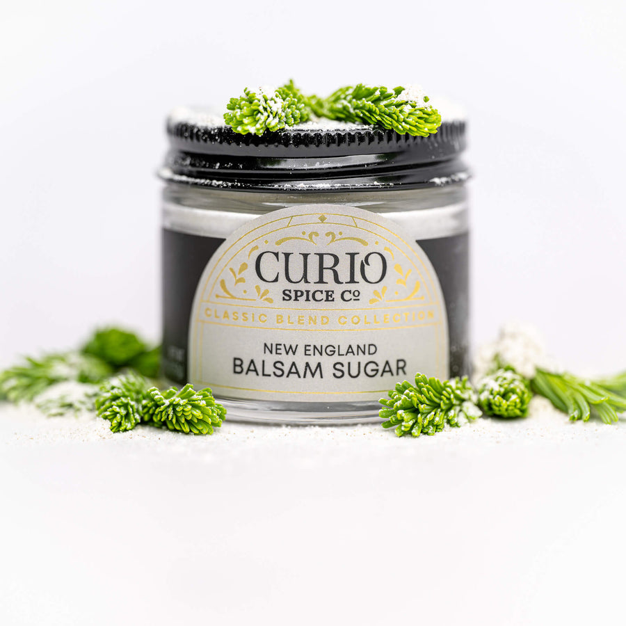 Jar of New England Balsam Sugar from Curio Spice Co. with greenery around on a white background