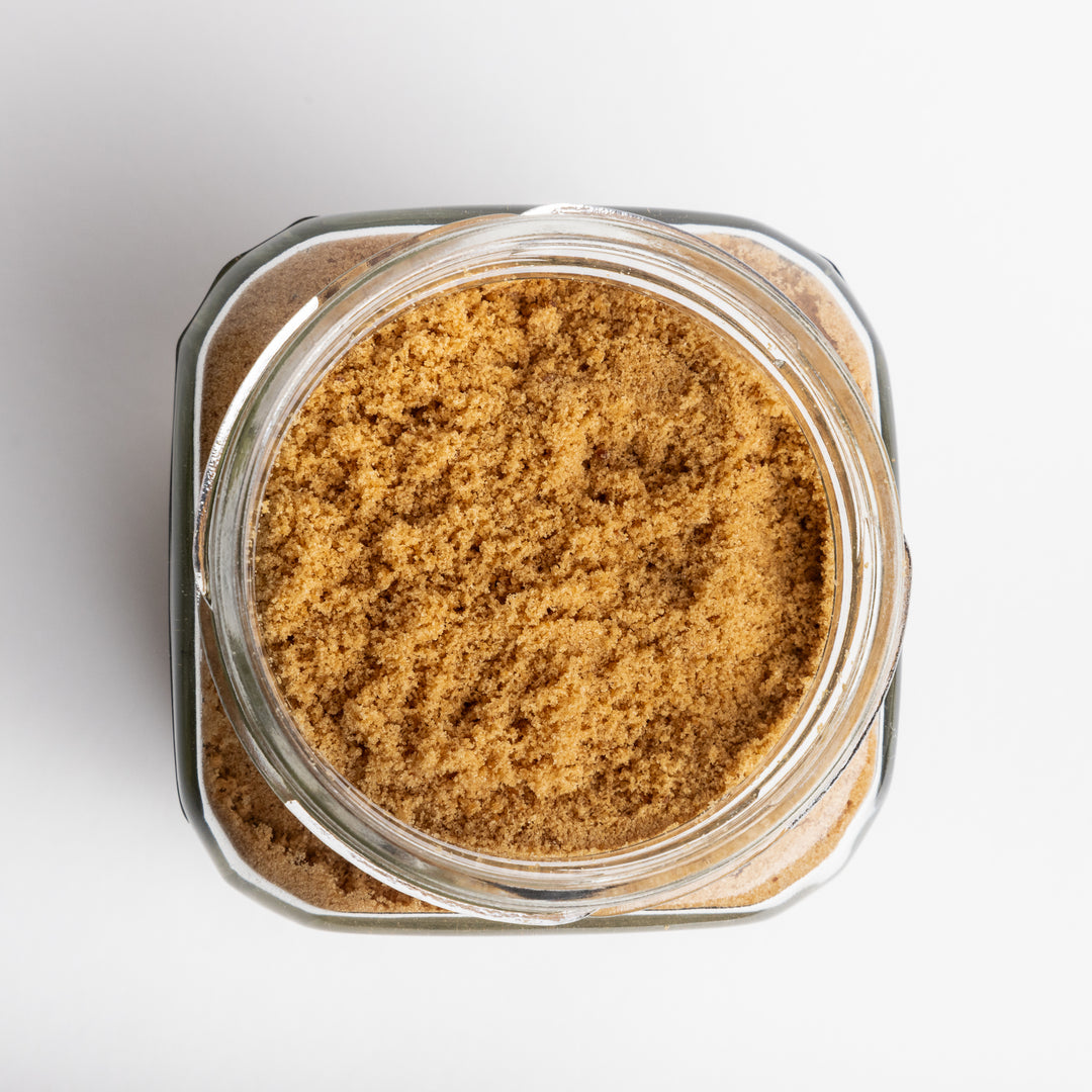 Glass jar filled with brown sugar on a white background