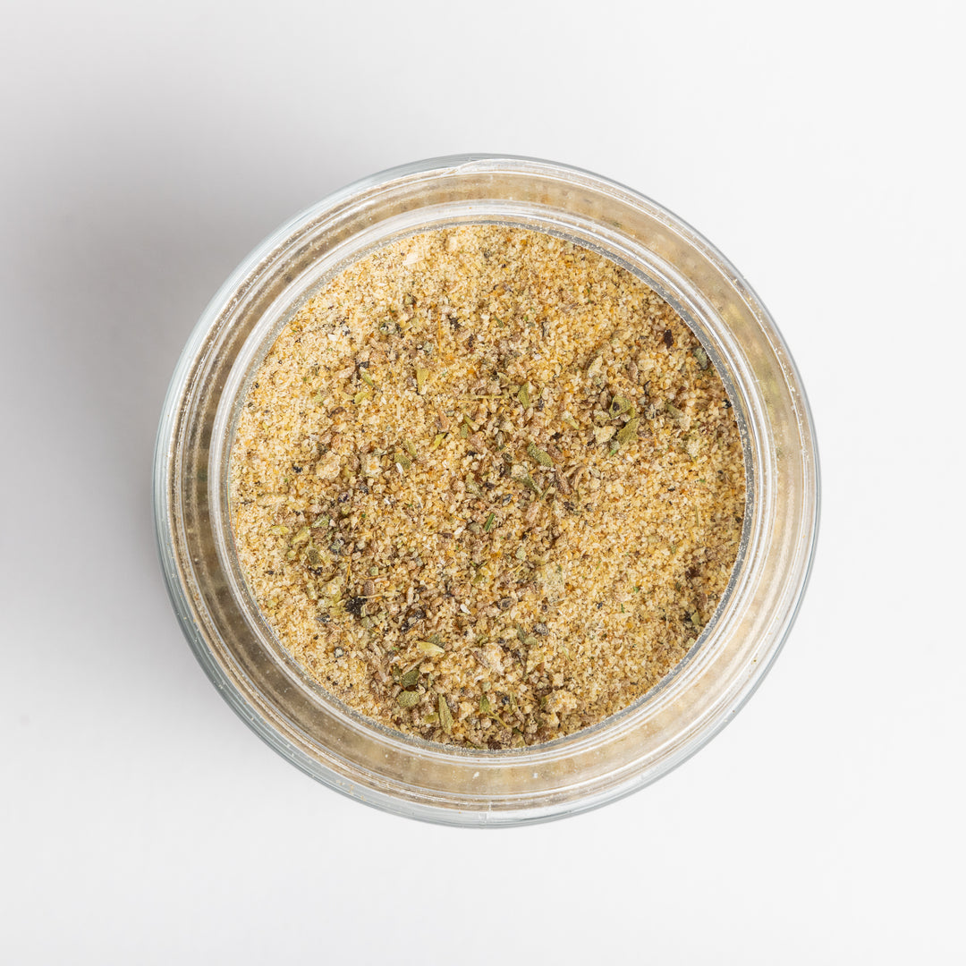 Clear glass jar filled with a spice mix on a light gray background