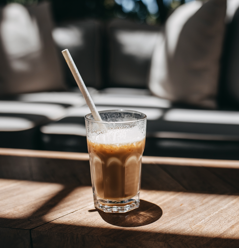 Glass of iced hojicha latte on a summery table.