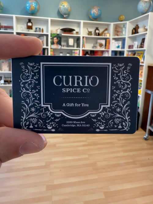 Black and white patterned Curio Spice Co gift card being held by hand