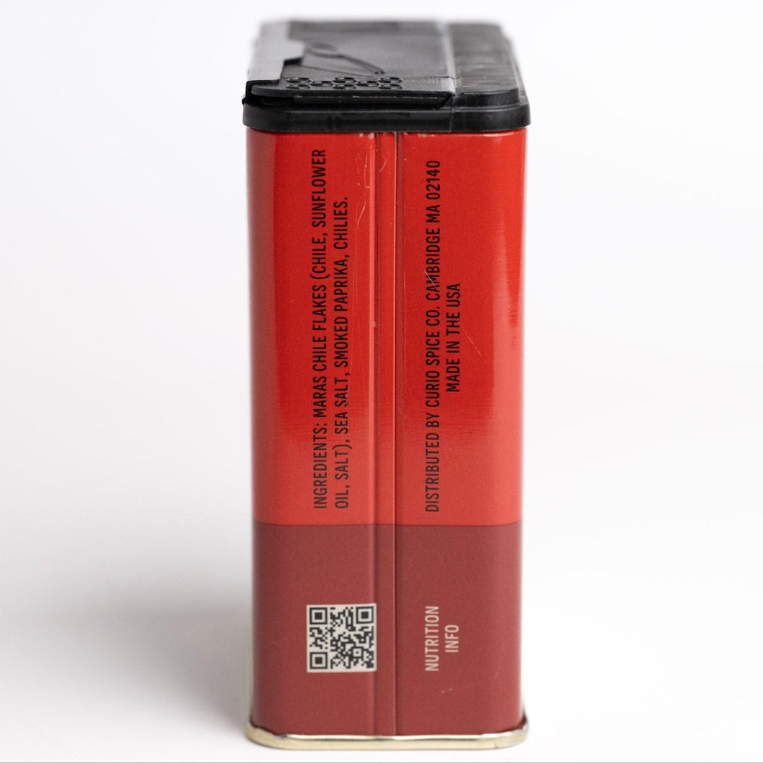Red spice container with black lid on a white background