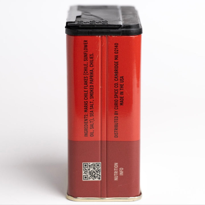 Red spice container with black lid on a white background