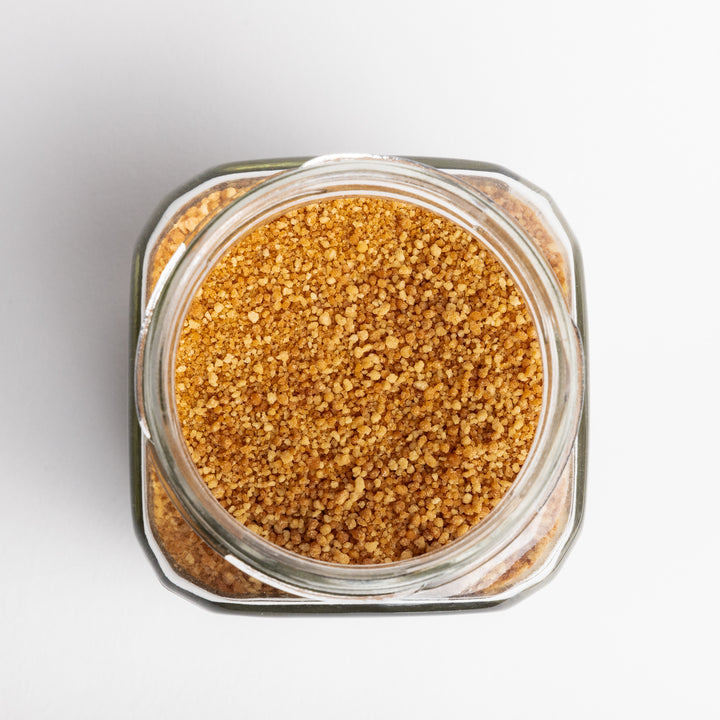 Glass jar filled with brown sugar on a light gray background