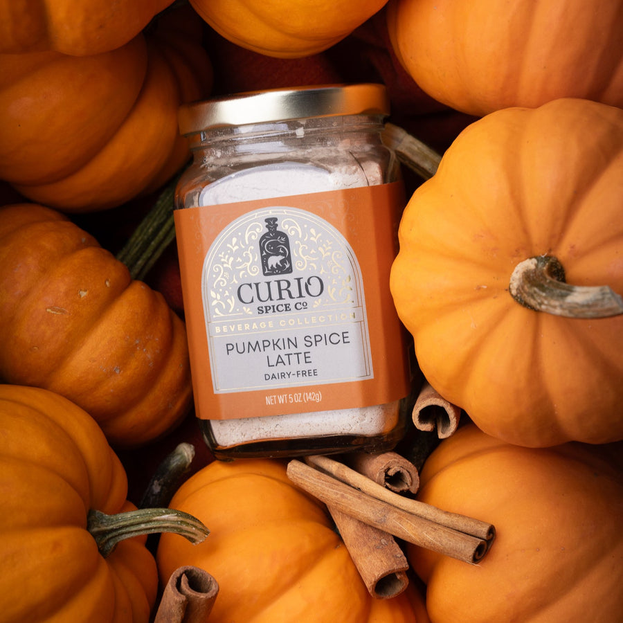 Jar of Curio Spice Pumpkin Spice Latte surrounded by pumpkins and cinnamon sticks