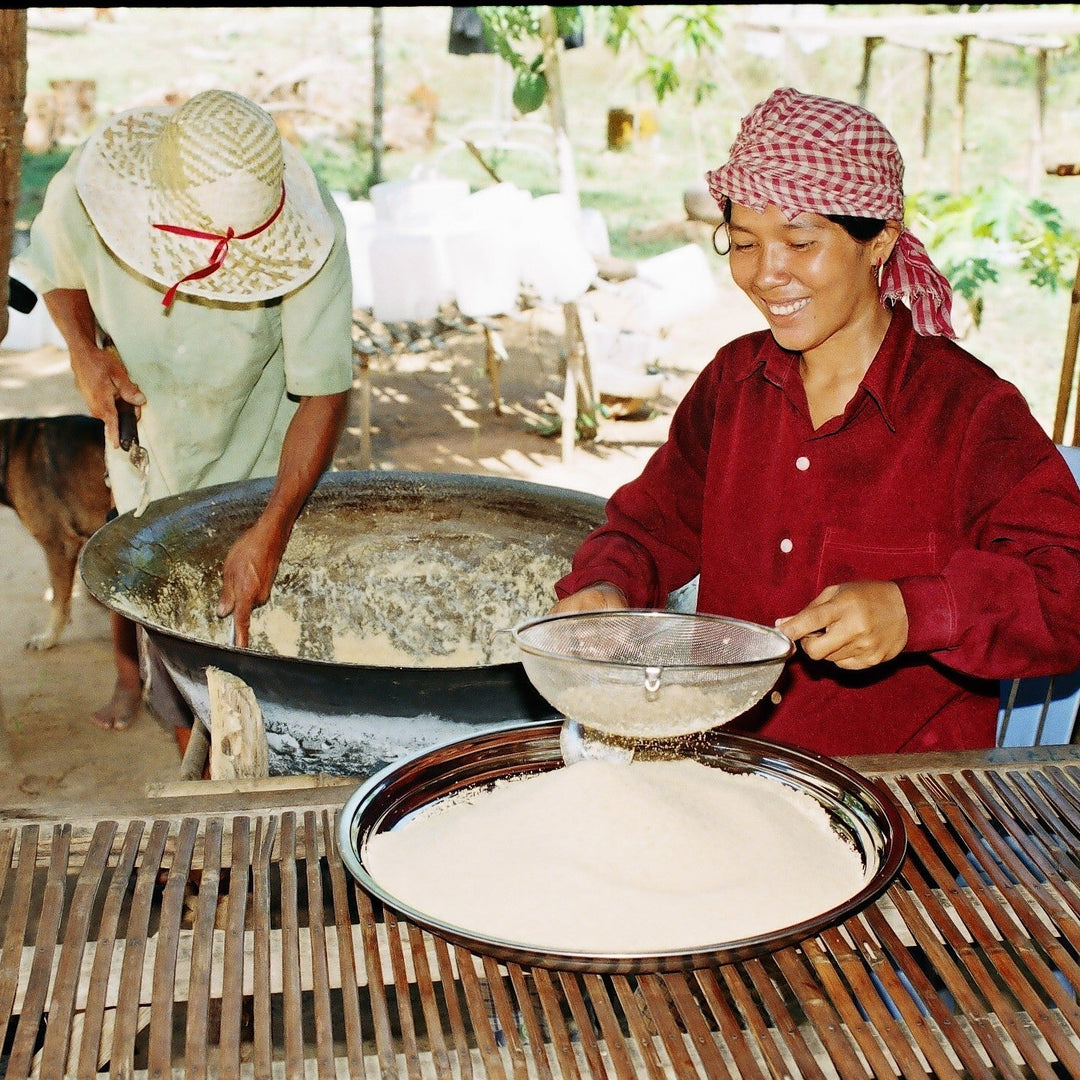 Two people working with a large bowl and tray outdoors.