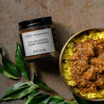 Jar of Ru's Dark-Roasted Curry Powder next to a bowl of Black Pork Curry