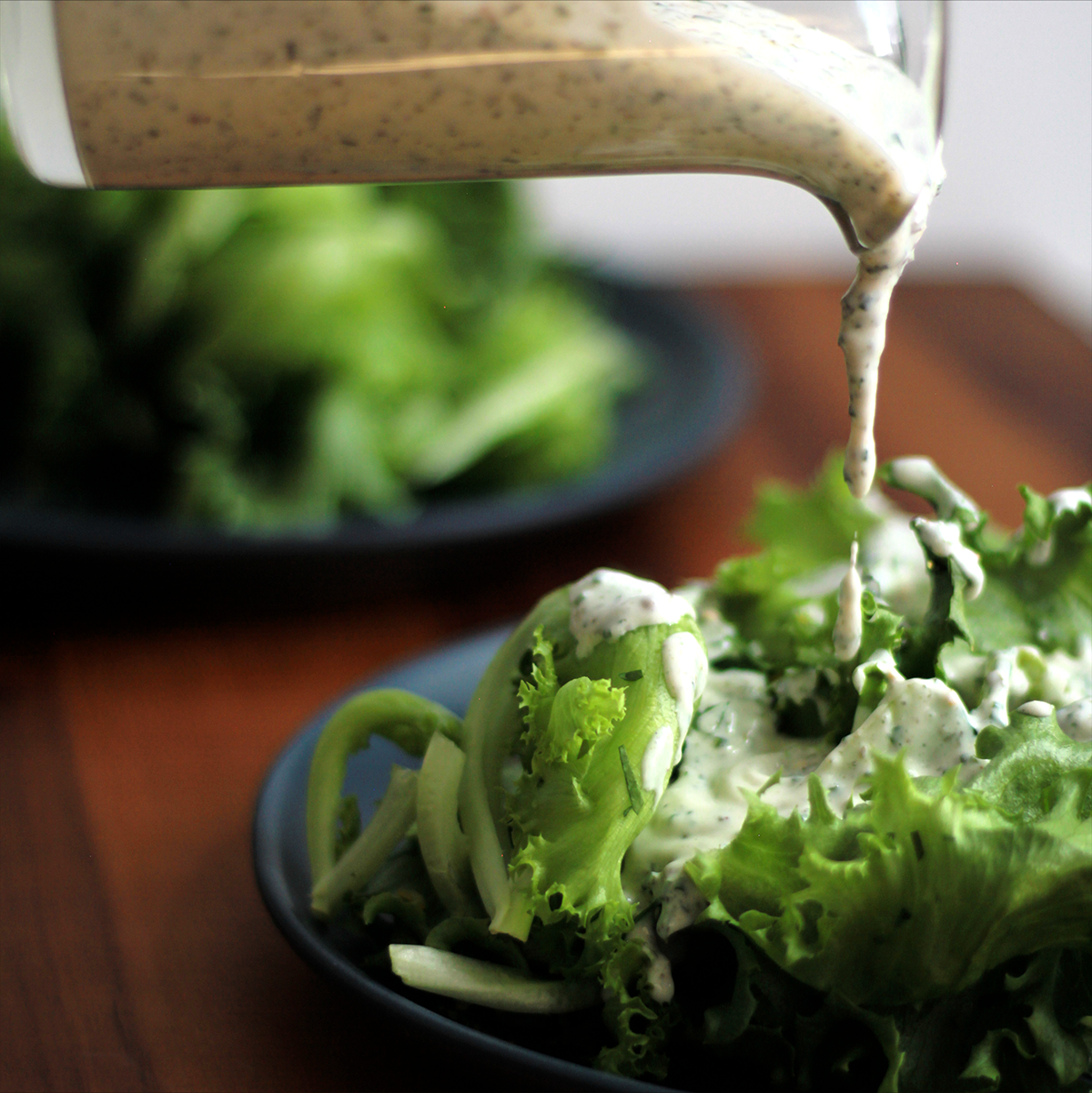 Dressing being poured over a salad on a wooden table