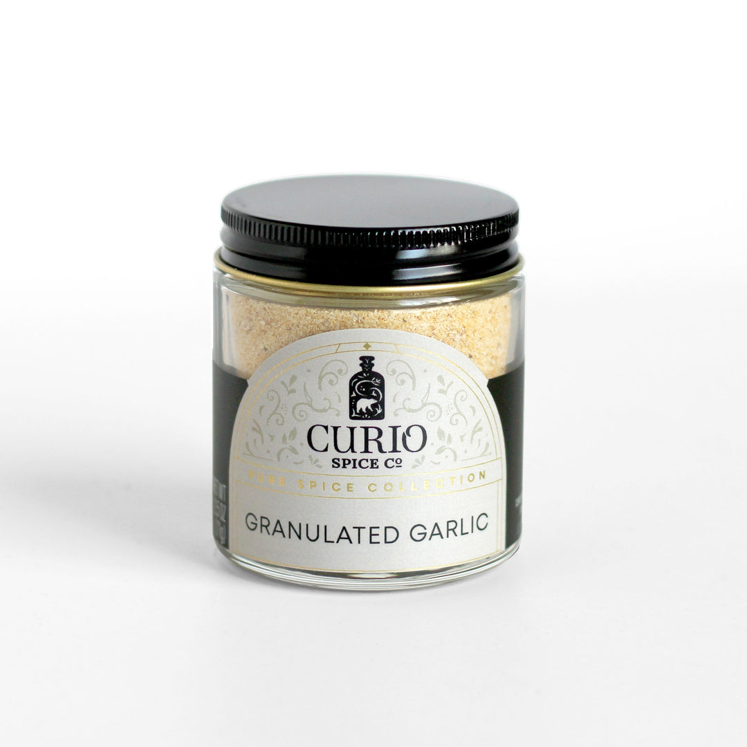 Granulated garlic in a Curio Spice clear glass jar.