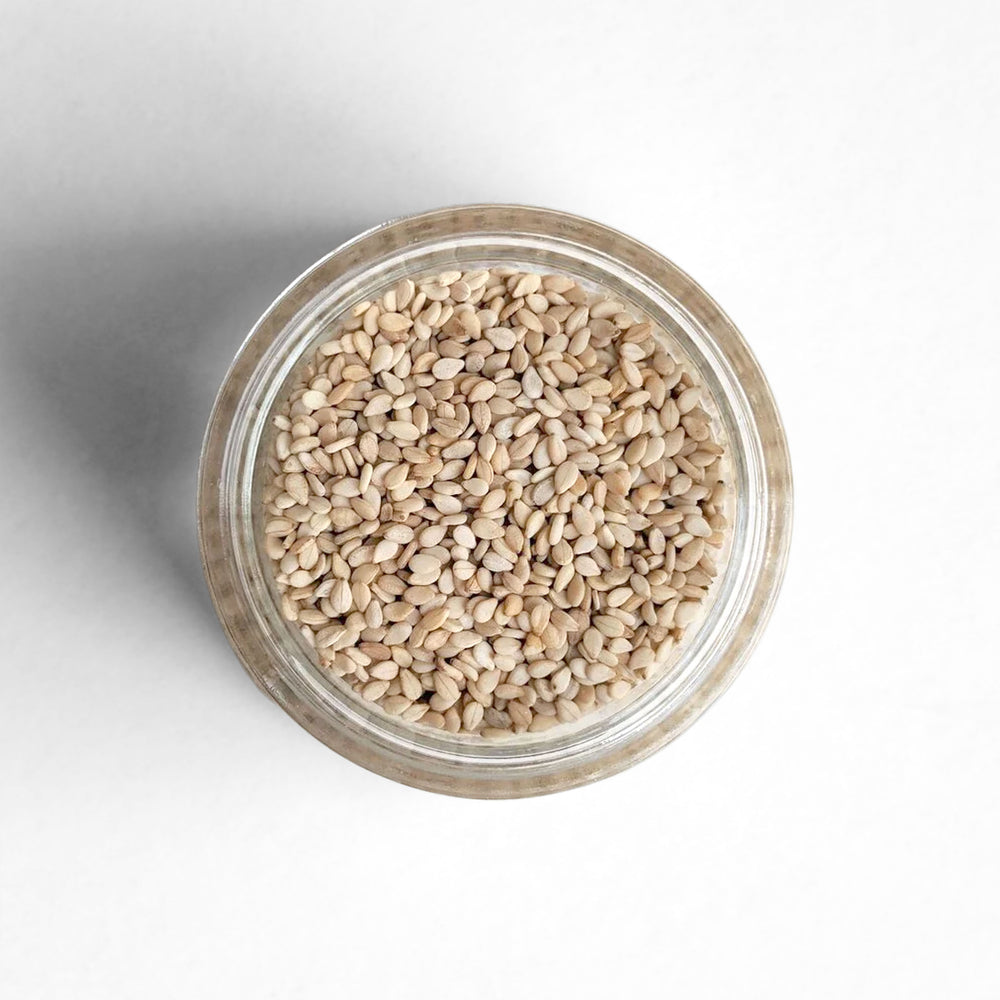 Curio Spice Co. fair-trade single origin sustainable white sesame seeds in a glass jar from above.