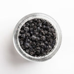 Clear jar filled with black peppercorns on a white background