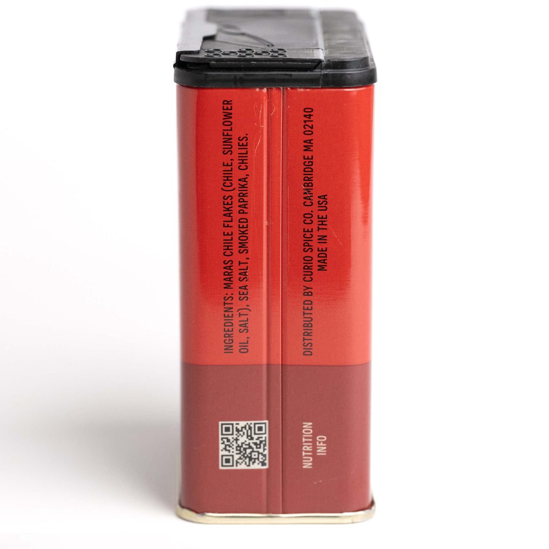 Red spice container with black lid on a white background