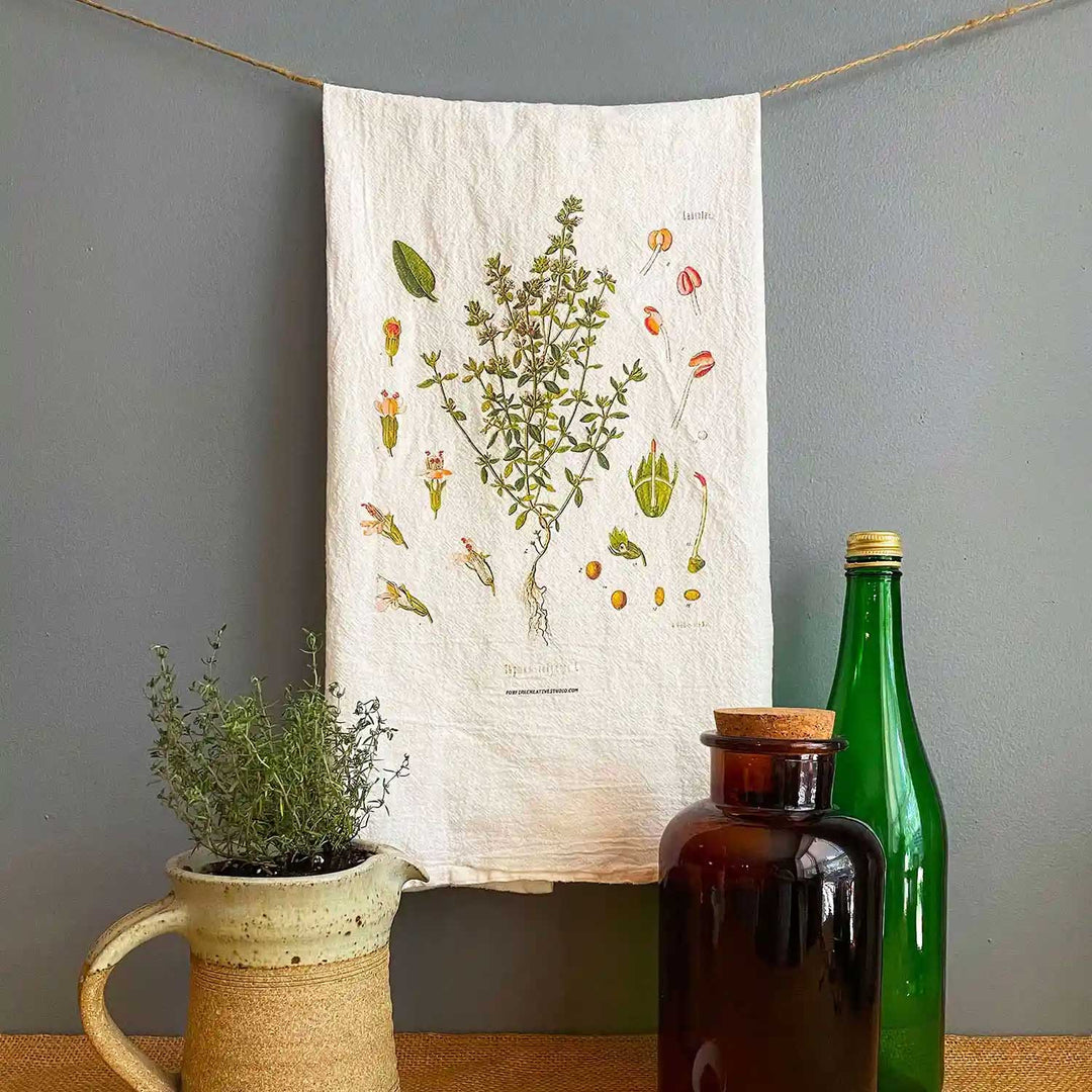 Tea towel with thyme flower against a gray backdrop