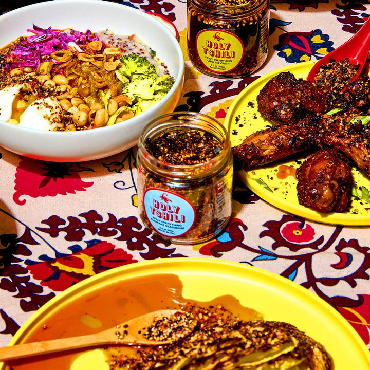 Holy tshili on a spread with wings, salads, and hummus