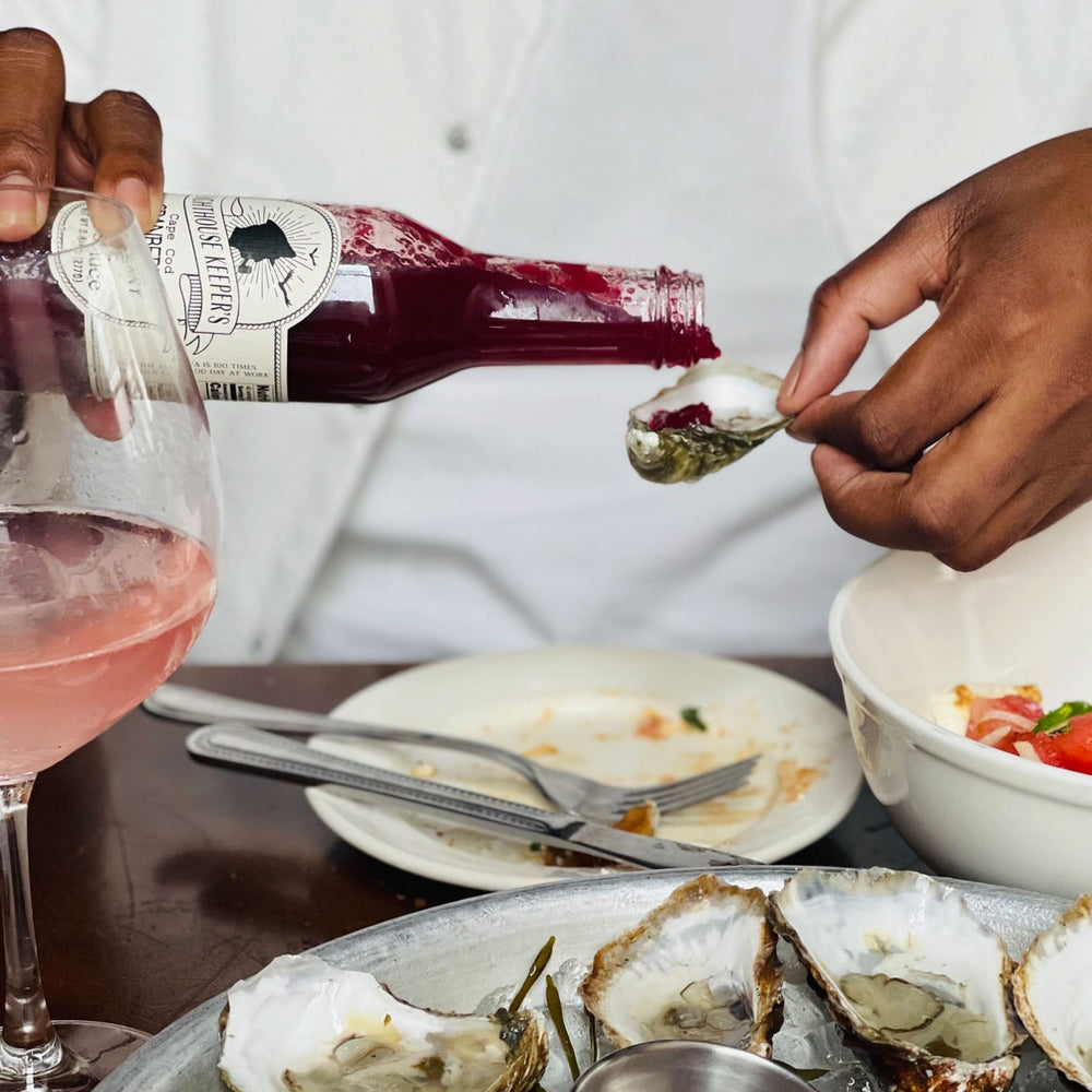 Cranberry Lime Hot Sauce being poured on oysters