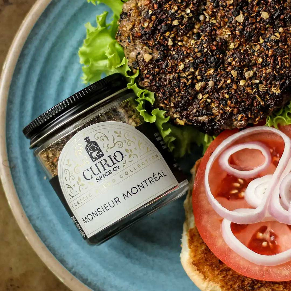 Burger with lettuce, tomato, and onions next to a jar of Monsieur Montreal