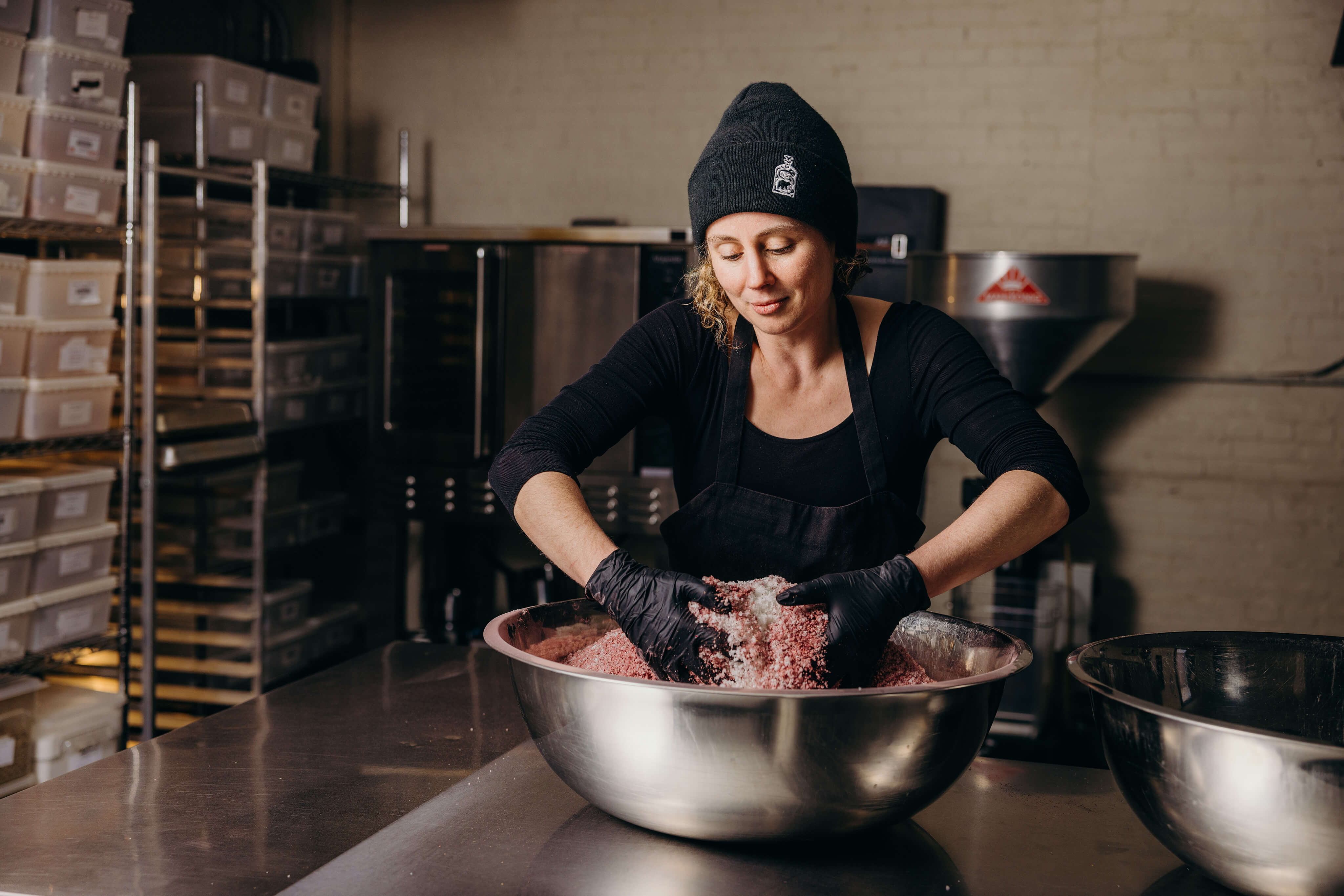Claire Cheney mixing a large bowl of spices in the production facility