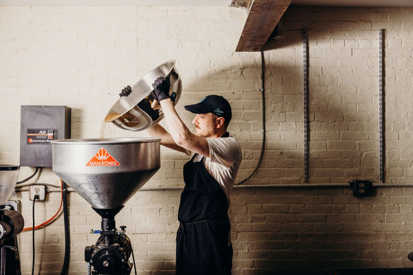 Spices being dumped from a large metal bowl into the grinder.