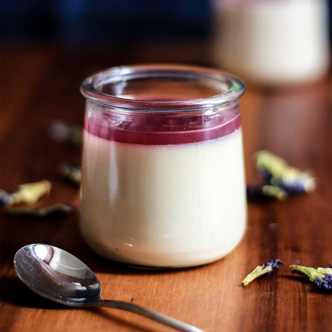 Butterfly Pea Flower Panna Cotta on a table with flower petals