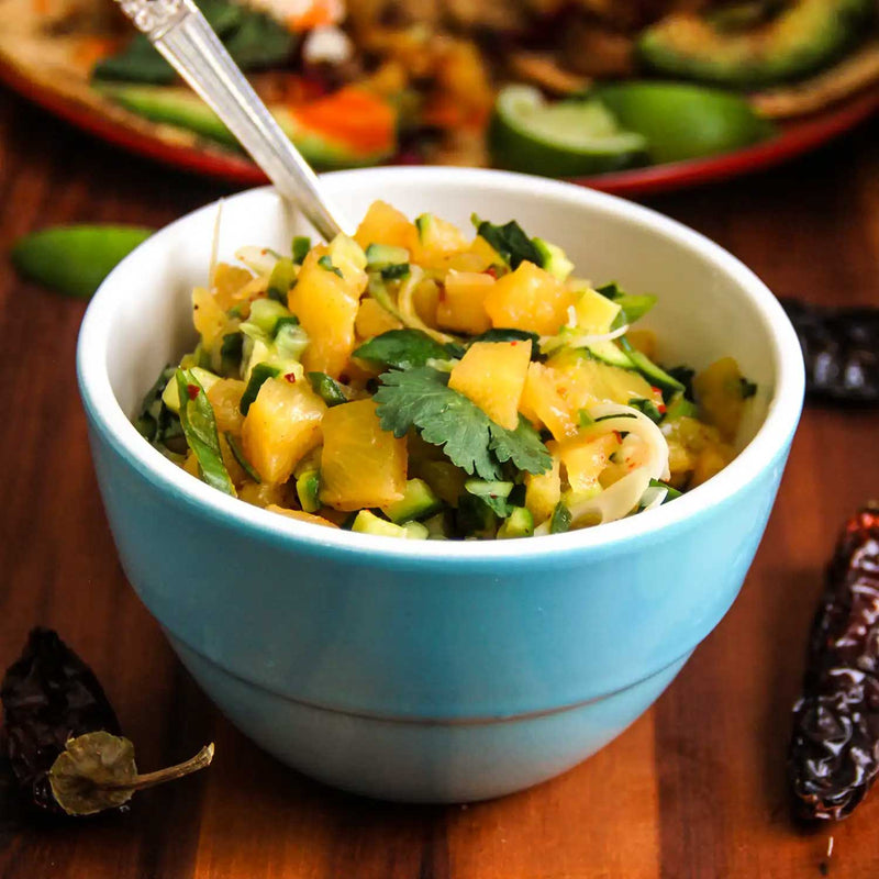Pineapple Salsa topped with Chipotle Chile in a blue bowl surrounded by chilies