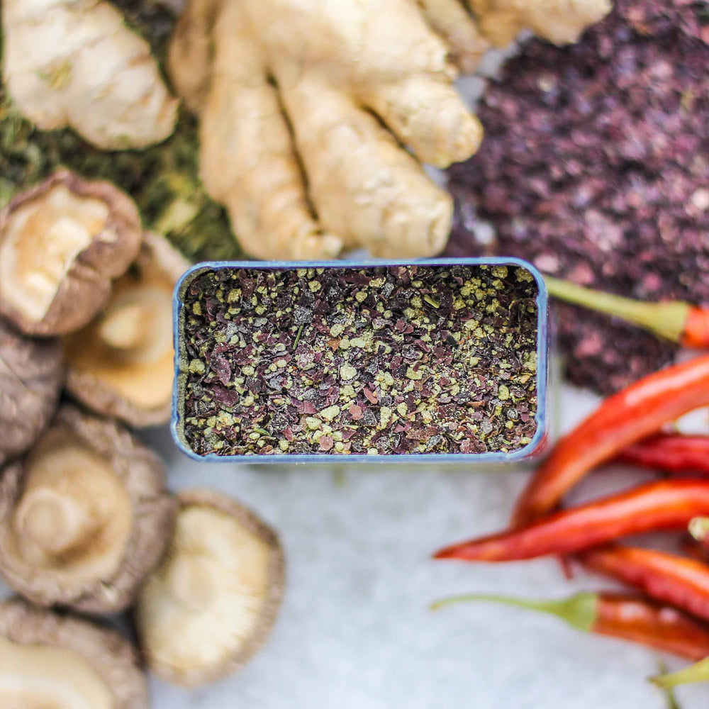 Top-down view showing the Curio Spice exclusive Supeq Spice blend with dried seaweed, sea salt, shiitake mushroom, ginger, nettle, and hot chile.