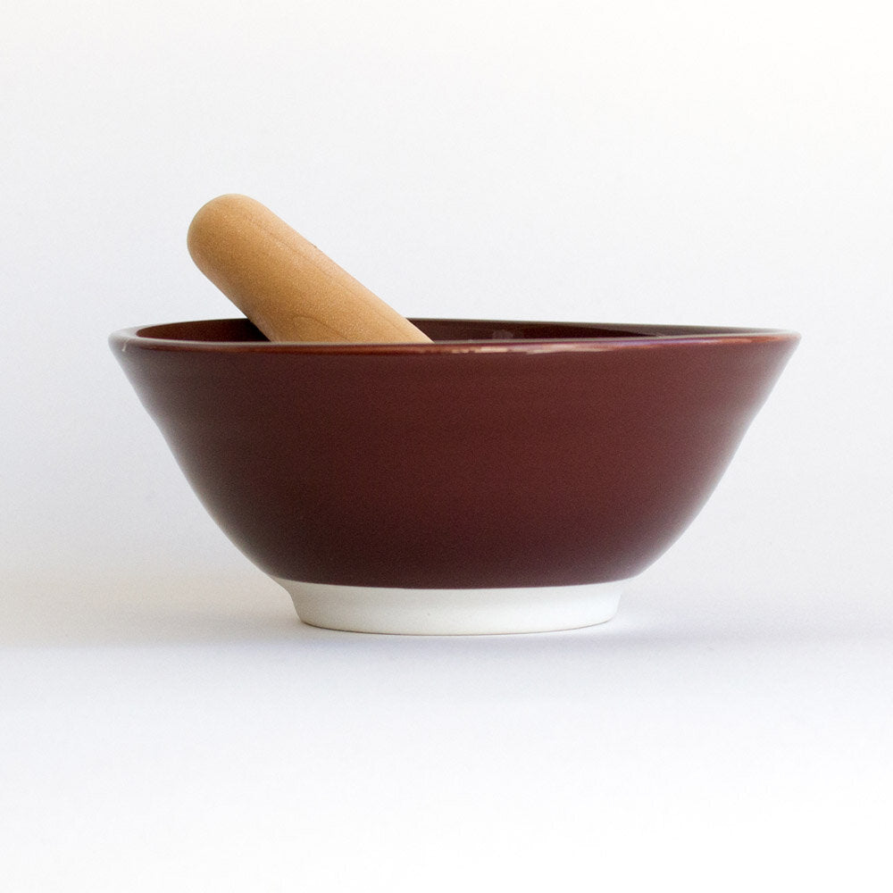 Side profile of Suribachi with its brown ceramic glaze and wooden pestle.