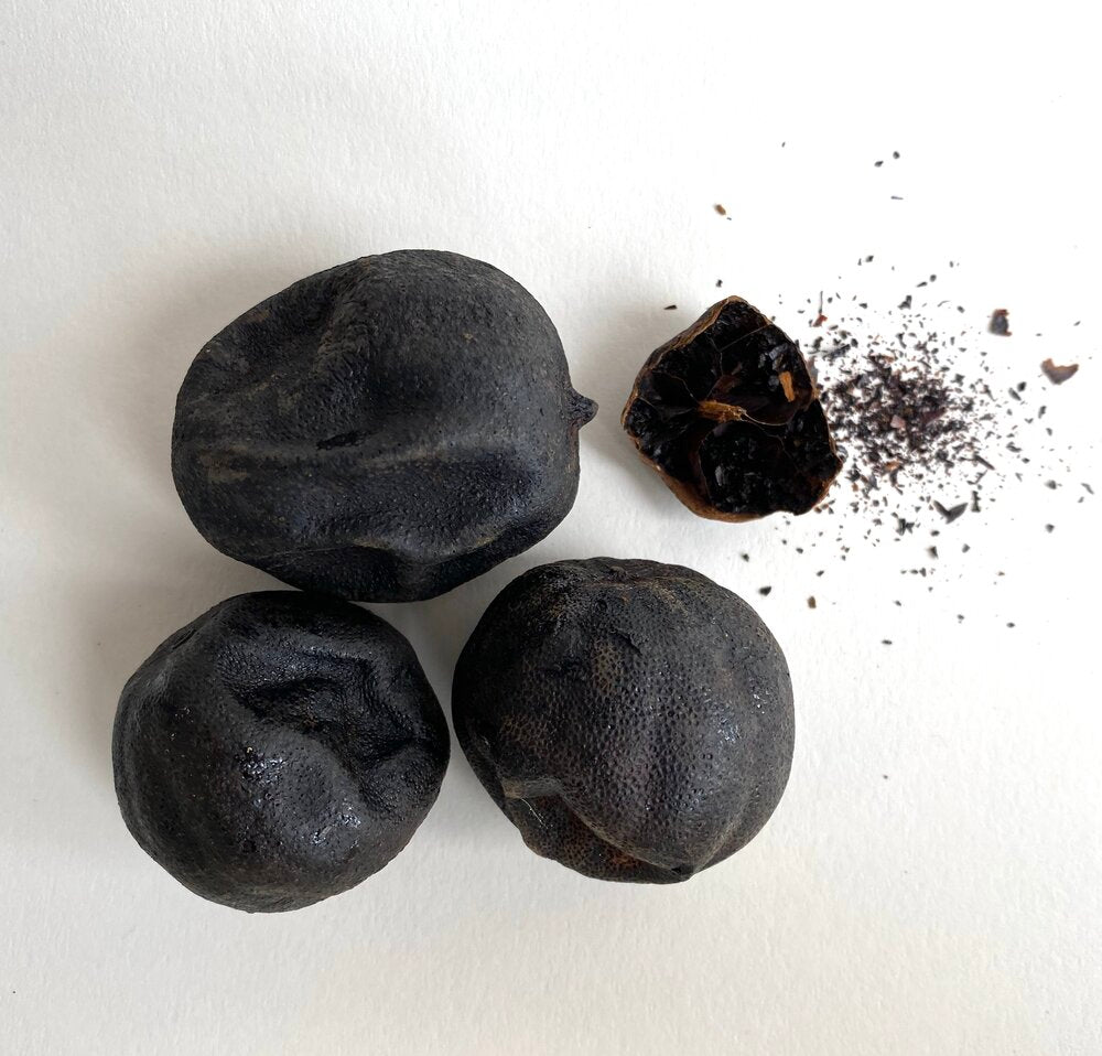 Black garlic bulbs, with one broken and scattered