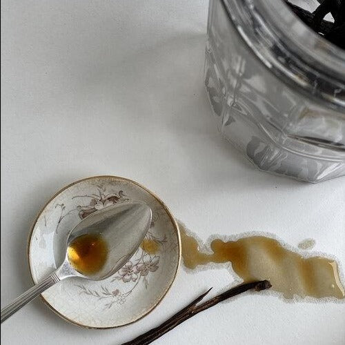 Madagascar vanilla extract on a spoon with a vanilla bean pod.
