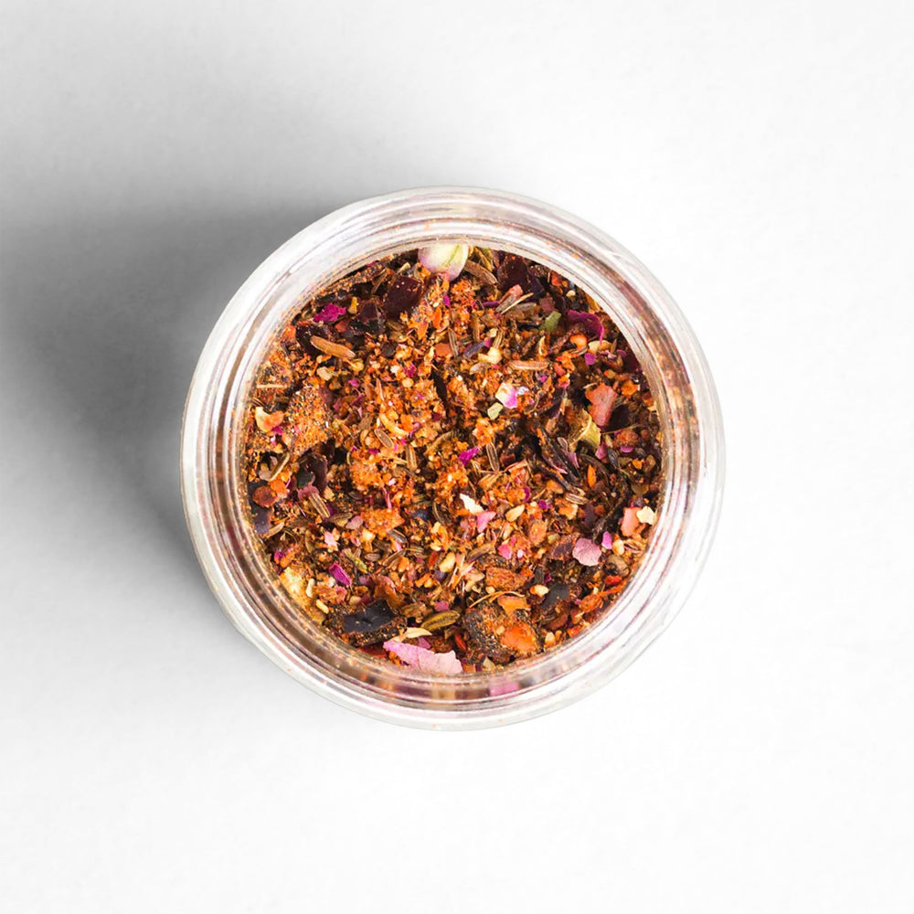 Top-down view of Rose Harissa with chilies, cumin, coriander, rose buds, grains of paradise, garlic, and sea salt.