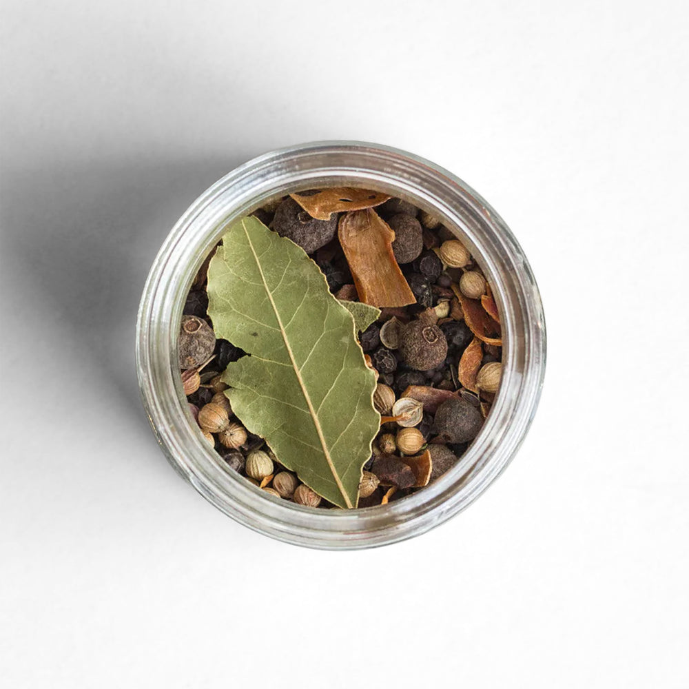 Top-down view of Traditional Pickling Spice shown with a bay leaf, allspice/pimento, cassia cinnamon, and brown mustard.