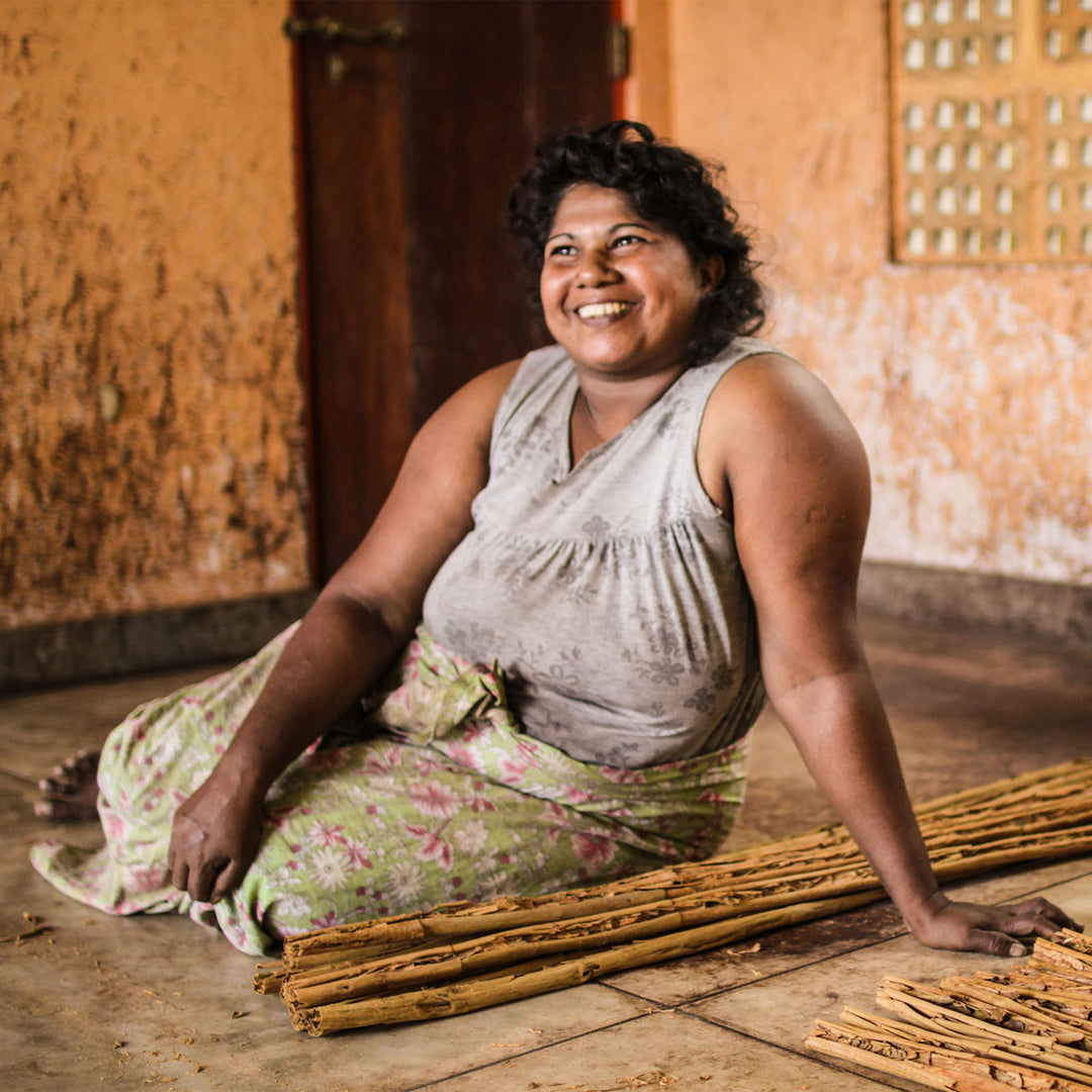 Woman sitting next to harvested Ceylon cinnamon.
