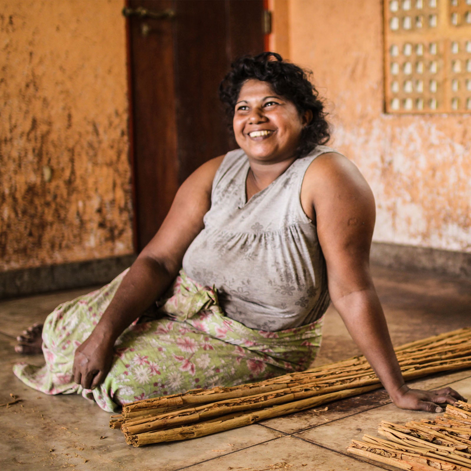 Woman sitting next to harvested Ceylon cinnamon.