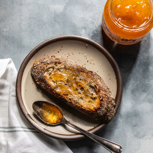 Image of Yuzu Marmalade spread on crusty bread with a spoon.